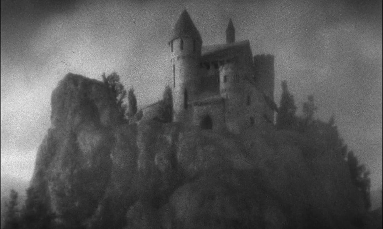 Prise de vue extérieure du château de Dracula. Un château en carton pâte sur une colline en carton pâte, avec des arbres en carton pâte.