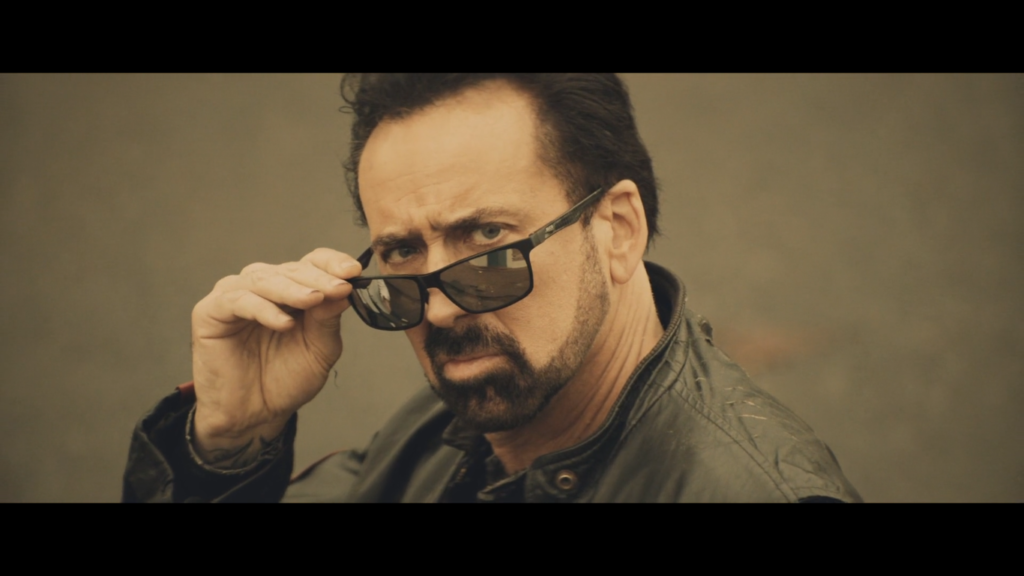 Nicolas Cage dans Willy's Wonderland, regarde suspicieusement au-dessus de ses lunettes.